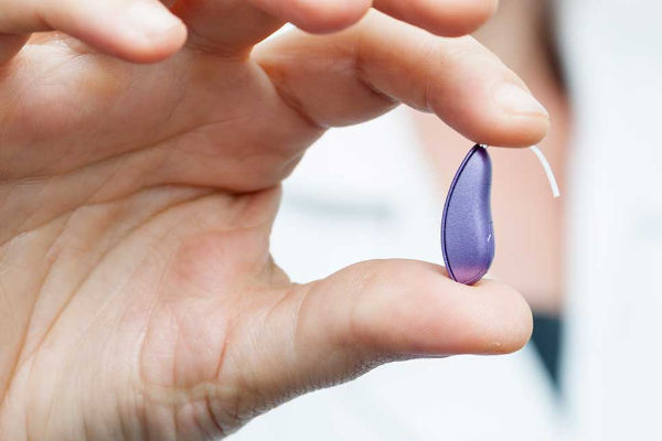 A hearing provider holding an RIC-type hearing aid