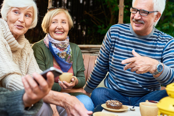 A group of seniors sharing a laugh at a table outside