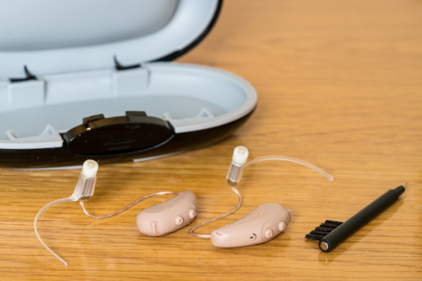 A pair of hearing aids pictured with a cleaning kit
