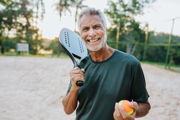 A senior man holding pickleball gear