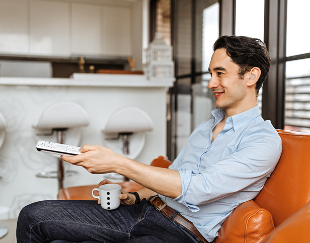 Man watching television while having coffee on sofa at home